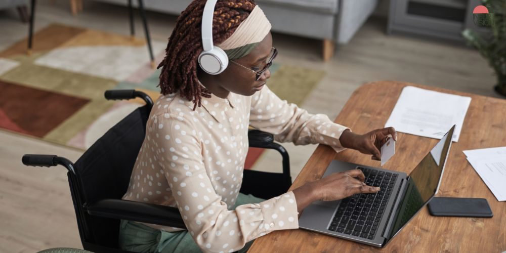 Frau im Rollstuhl arbeitet am Laptop Eine Frau mit Handicap die am Laptop arbeitet